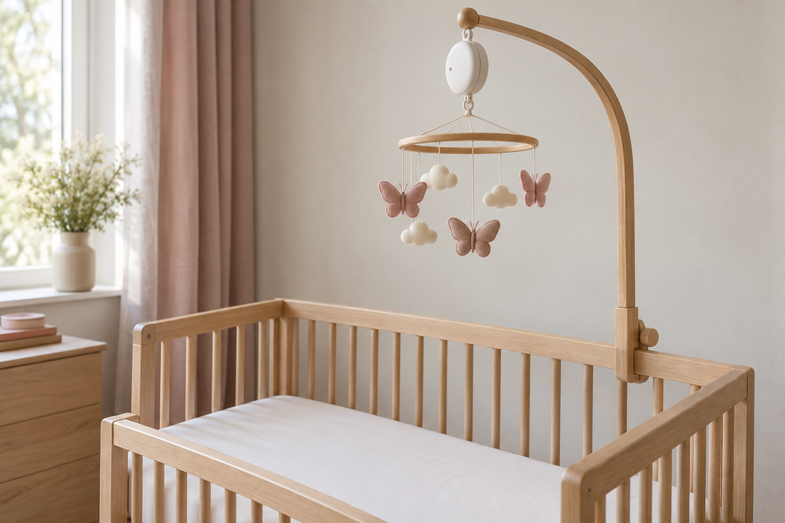 Dusty rose butterfly and cream cloud mobile with a white music box high above a bare oak crib